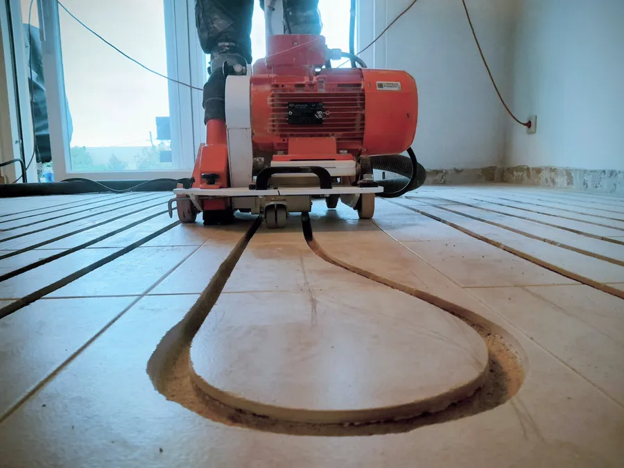 Milling machine cutting a channel into an existing tiled floor, dust hose attached