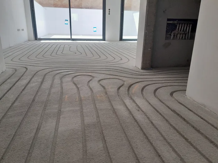 Milled channels across a large open-plan villa floor mid-installation
