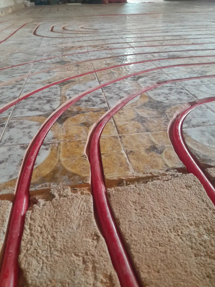 Heating pipe curved through an existing decorative tiled floor, close up
